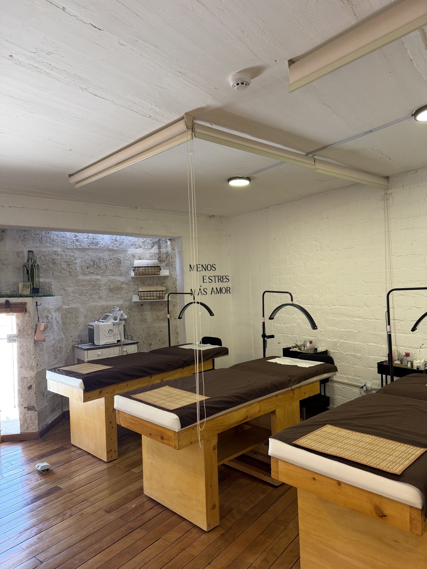 Sala de tratamiento con camillas de madera y muro de piedra sillar en HerStudio