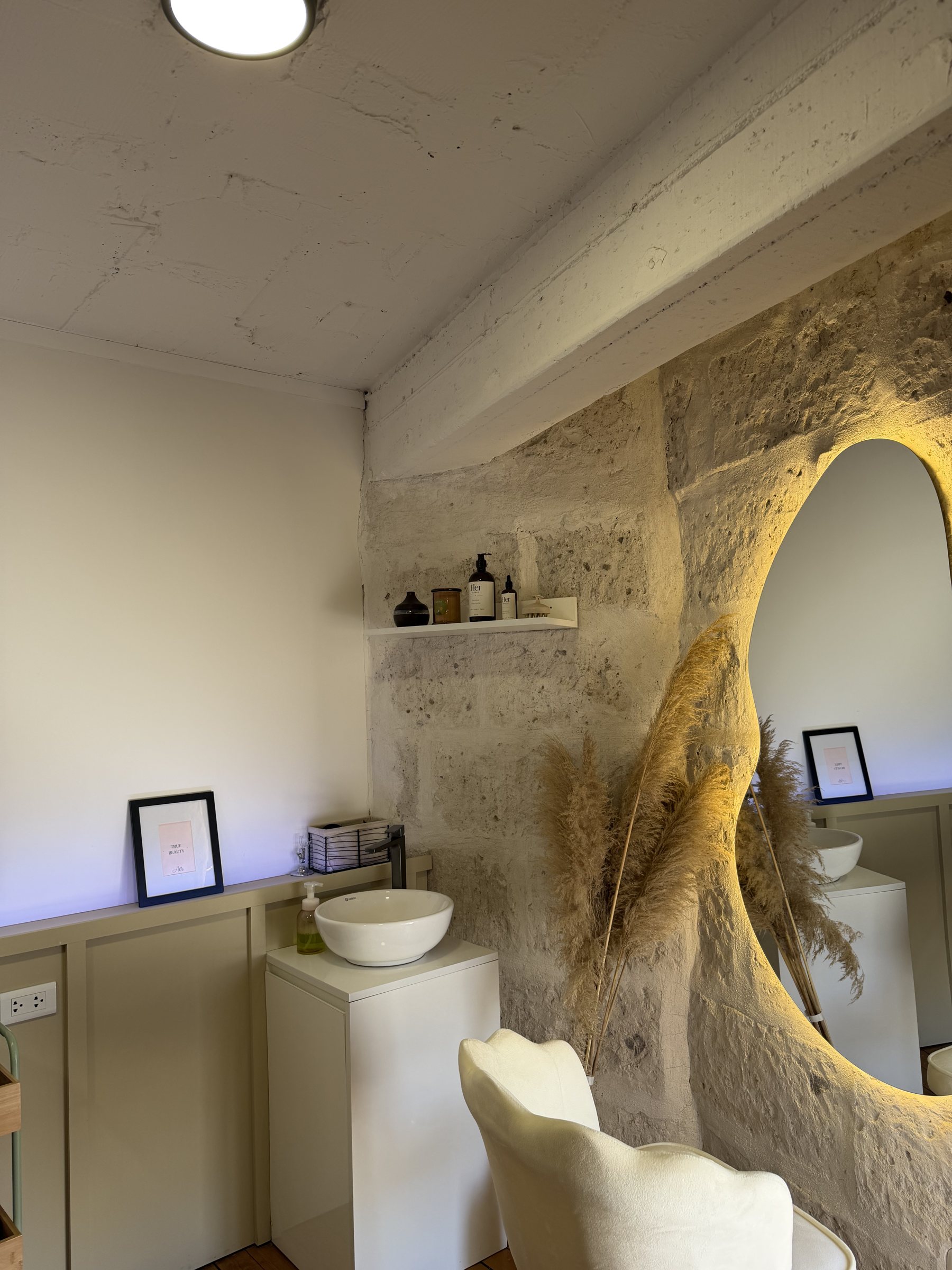 Espejo ovalado con iluminación cálida y sillón boucle en HerStudio